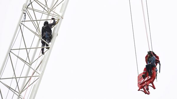 A woman is rescued from a downtown Toronto crane early Wednesday, April 26, 2017. Some streets in the downtown core were closed as dozens of construction workers and commuters gazed skyward to watch police and firefighters try to rescue the woman who got stuck atop the tall construction crane. (Frank Gunn/The Canadian Press via AP)