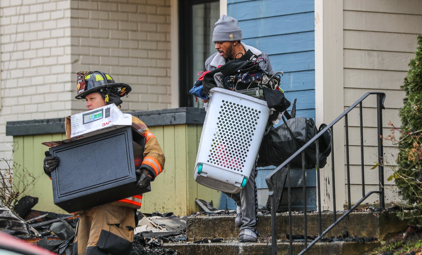 A firefighter helps a resident remove belongings from his burned out home at The Park on Windy Hill Apartments in January 2021. Salt Lake City-based Bridge Investment Group acquired this Marietta complex and three other suburban Atlanta properties since 2019 that the Journal-Constitution found to be persistently dangerous. (John Spink / John.Spink@ajc.com)