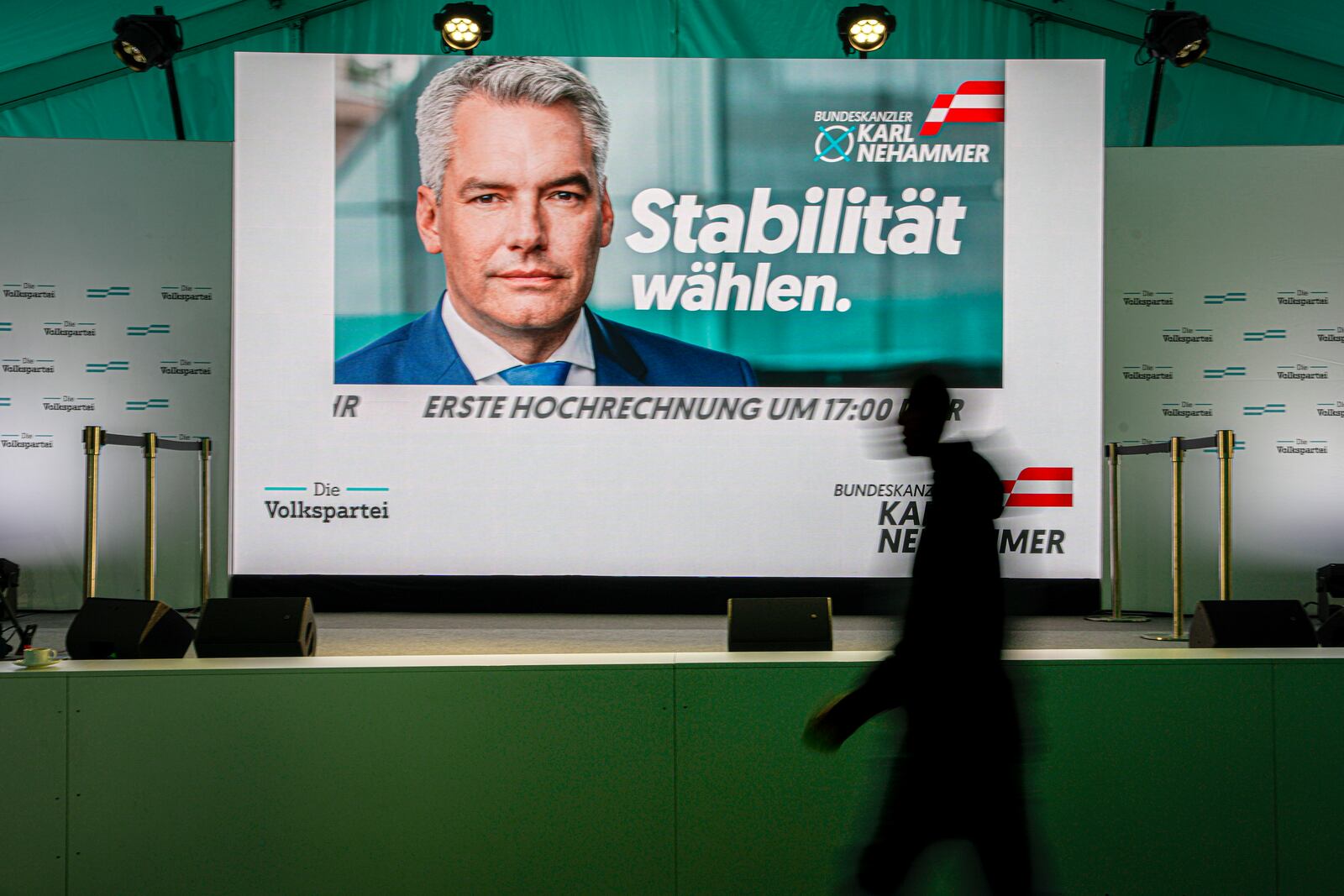 A person walks by a display showing electoral visuals of Austrian Chancellor Karl Nehammer at the OVP, Austrian People's Party, headquarters in Vienna, Austria, Sunday, Sept. 29, 2024, after casting his vote in the country's national election. (AP Photo/Andreea Alexandru)