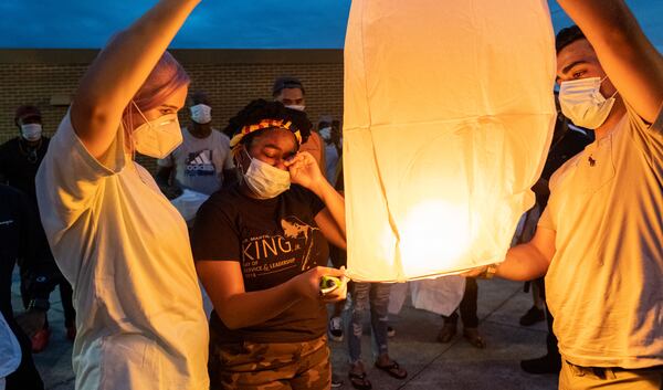 Amber Gregory, center, wipes away a tear while helping launch a sky lantern in honor of her brother Kyle Gregory. (Ben Gray for the Atlanta Journal-Constitution)