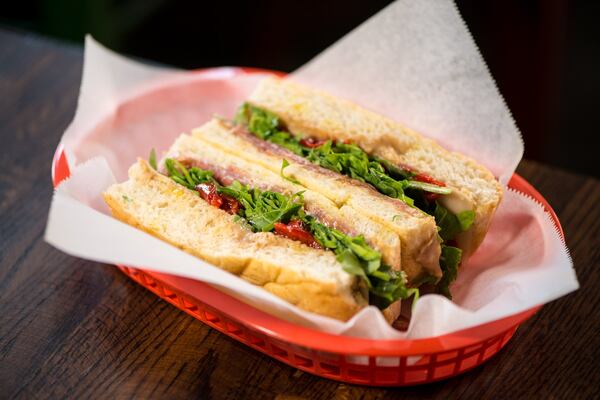 Pan de Jamon Y Queso sandwich with Spanish foccacia, serrano ham, manchego, almond-date spread, arugula, and piquillo agridulce. Photo credit- Mia Yakel.