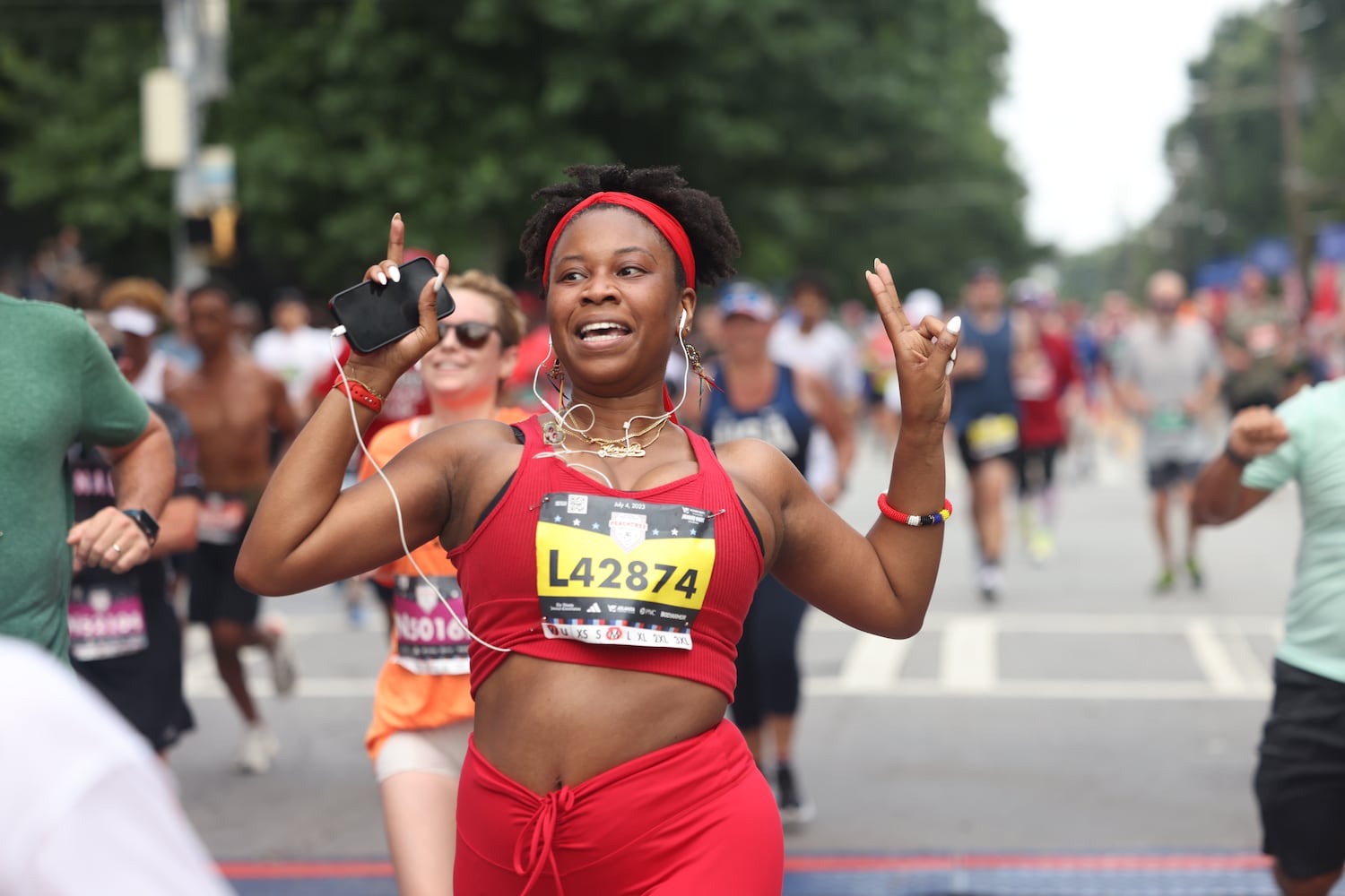 Runner celebrates at the finish of the 54th running of the Atlanta Journal-Constitution Peachtree Road Race in Atlanta on Tuesday, July 4, 2023.   (Jason Getz / Jason.Getz@ajc.com)