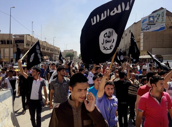 FILE - In this June 16, 2014 file photo, demonstrators chant pro-Islamic State group slogans as they carry the group's flags in front of the provincial government headquarters in Mosul, Iraq. Under its leader, Iraqi jihadi Abu Bakr al-Baghdadi, the Islamic State group top command is dominated by former officers from Saddam Hussein's military and intelligence agencies, according to senior Iraqi officers and top intelligence officials. (AP Photo, File)