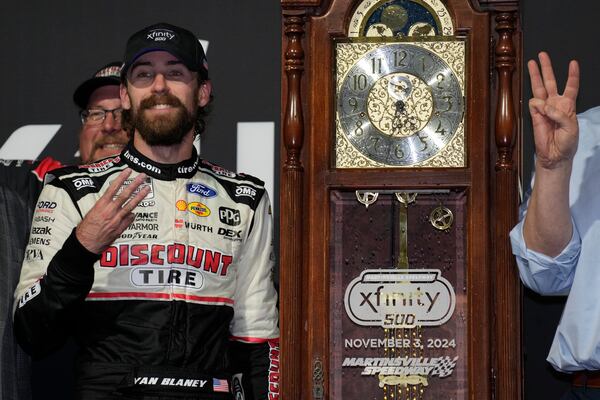 Ryan Blaney, front left, poses with the trophy in Victory Lane after winning a NASCAR Cup Series auto race at Martinsville Speedway in Martinsville, Va., Sunday, Nov. 3, 2024. (AP Photo/Chuck Burton)