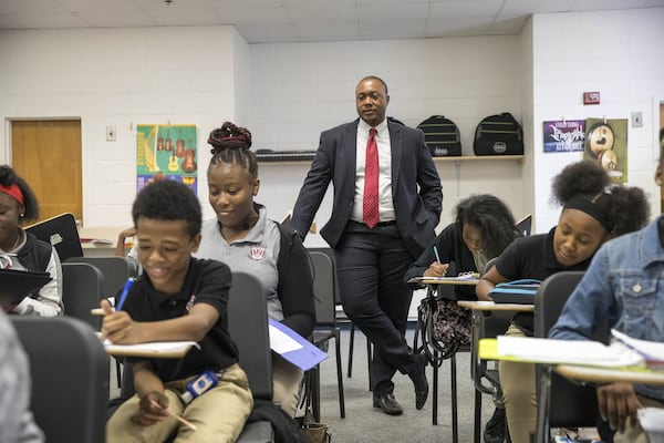 Artesius Miller (center) watches over a music class Thursday at Utopian Academy for the Arts in Ellenwood. Miller, 31, is founder and executive director of the charter school. (ALYSSA POINTER/ALYSSA.POINTER@AJC.COM)