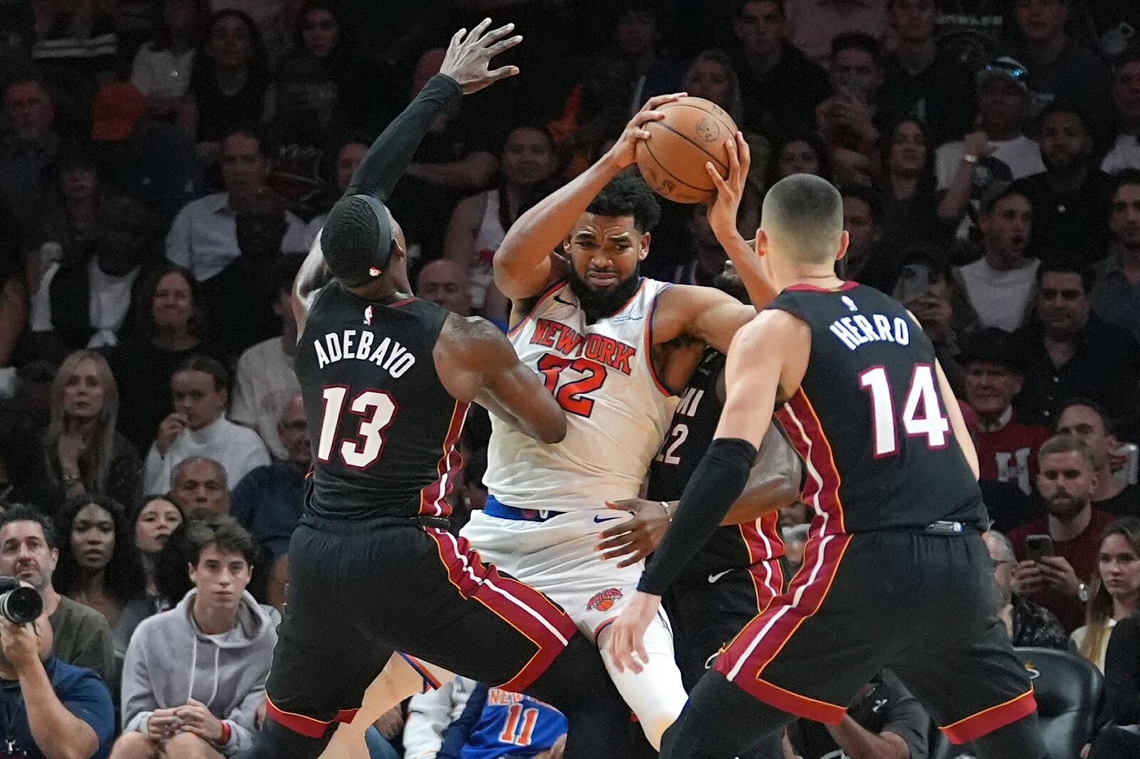 Miami Heat center Bam Adebayo (13) and guard Tyler Herro (14) defend New York Knicks center Karl-Anthony Towns (32) during the second half of an NBA basketball game, Wednesday, Oct. 30, 2024, in Miami. (AP Photo/Lynne Sladky)