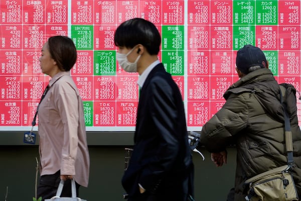 People walk in front of an electronic stock board showing Japan's Nikkei index at a securities firm Thursday, Feb. 27, 2025, in Tokyo. (AP Photo/Eugene Hoshiko)