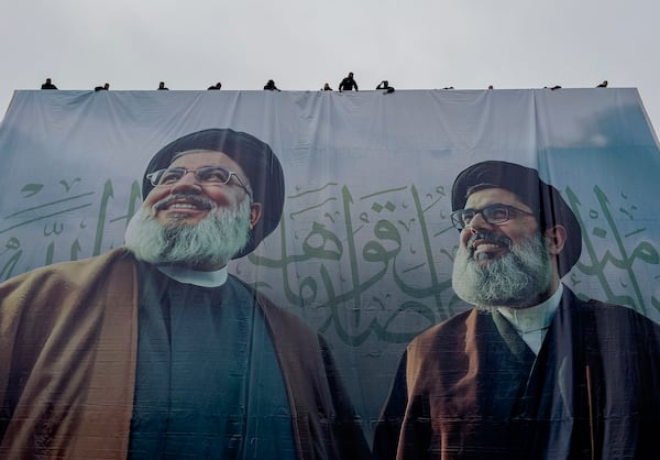 Workers display a giant banner with the portraits of the late Hezbollah leaders Sayyed Hassan Nasrallah, left, and Sayyed Hashem Safieddine, during preparation, a day ahead of their funeral procession at Beirut's City Sportive stadium, in Beirut, Lebanon, Saturday, Feb. 22, 2025. (AP Photo/Hussein Malla)