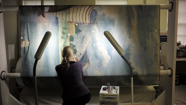 In this Tuesday, Nov. 7, 2017 photo textile conservator Kate Tarleton, of Rochester, Mass., works to restore a portion of the 1848, "Grand Panorama of a Whaling Voyage Round the World," at the New Bedford Whaling Museum, in New Bedford, Mass. The artwork is believed to be the longest painting in the world at about a quarter mile long. The panorama toured the U.S. after it was completed in 1848. (AP Photo/Steven Senne)