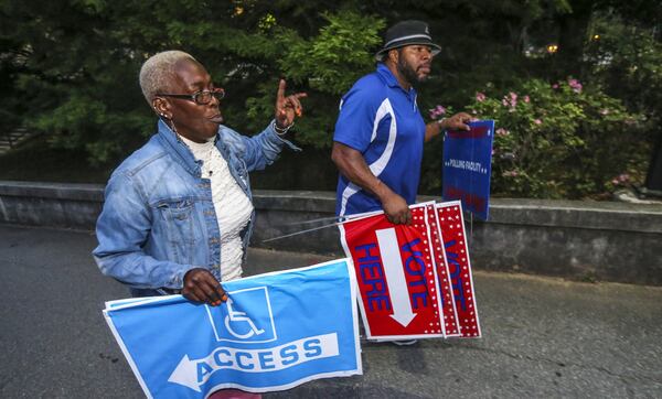 Poll workers Raphallia Edwards and Chris Nolan prepare signage at Henry W. Grady High School in Atlanta in May 22. A lawsuit has been filed challenging maps approved by the Republican-led Georgia General Assembly in 2011, saying state lawmakers gerrymandered the state’s 14 congressional districts in a way that violates the Voting Rights Act, which prohibits voting discrimination against racial minorities. JOHN SPINK/JSPINK@AJC.COM