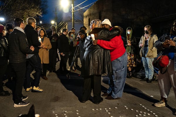 Elisabeth Omilami, with Hosea Helps, hugs Alison Johnson, with the Housing Justice League, while they hold a joint vigil for the unhoused man who was killed. Ben Hendren/AJC