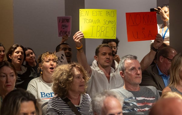 Miami Beach resident Phillip Carter holds up protest signs sign during the public speaking portion as the City Commission was expected to discuss Mayor Steven Meiner's proposal to terminate a lease and cut financial support for the independent film theater on Wednesday, March 19, 2025 in Miami Beach, Fla. (Jose Iglesias /Miami Herald via AP)