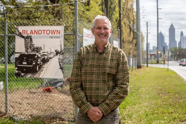 Artist Gregor Turk stands near one of his banners, which are hung on the fence of the city of Atlanta Department of Watershed Management Water Treatment Plant in Blandtown. (Alyssa Pointer / Alyssa.Pointer@ajc.com)