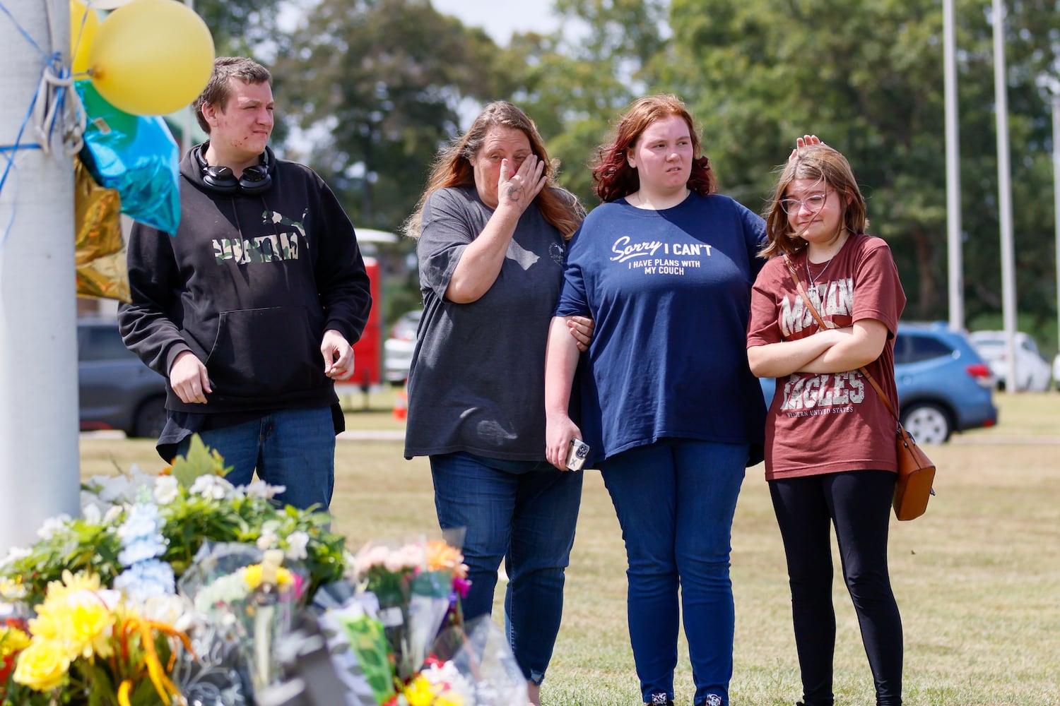 April Johnson, second left, mother of 11-grade students at Apalachee High School Gavin and Jazmine Johnson, along with Hanna Thompson, right, reacts as they pay respect by the flag pole on Thursday, September 5, 2024. This came a day after a 14-year-old opened fire at a Barrow County high school on Wednesday morning, killing two students and two teachers and injuring nine others. (Miguel Martinez/AJC)