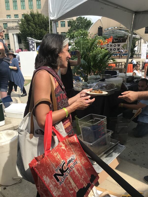 AJC dining editor Ligaya Figueras reaches for a plate of paella from chef José Andrés at a food festival in Asheville, North Carolina. CONTRIBUTED BY LIGAYA FIGUERAS