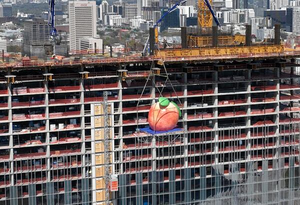 A gigantic peach is lifted up to the top during topping out ceremony of Signia by Hilton Atlanta at Georgia World Congress Center, Thursday, March 23, 2023, in Atlanta. Plans are in motion for GWCCA’s new headquarter hotel Signia by Hilton Atlanta. Featuring close to 1,000 rooms, this premier full-service hotel will sit on the northwest corner of the campus, adjacent to Building C of Georgia World Congress Center. (Hyosub Shin / Hyosub.Shin@ajc.com)