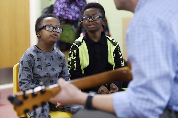 Roy Joyner plays a guitar while Ashton Hall, 9, right, and Tony Coleman, 9, left, listen intently during a music therapy session at Campbell Elementary School in Fairburn. Joyner works in several schools to help special-needs children through music therapy. (DAVID BARNES / SPECIAL)