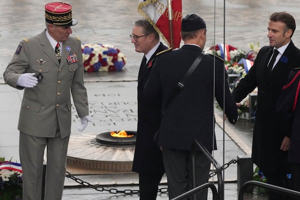 French President Emmanuel Macron, right, and British Prime Minister Keir Starmer, center, walk past the flame of the Tomb of the Unknown Soldier during ceremonies marking the 106th anniversary of the Armistice, a celebration of their countries' friendship, as nations across the world pay tribute to their fallen soldiers in World War I, Monday, Nov. 11, 2024 in Paris, (AP Photo/Michel Euler, Pool)