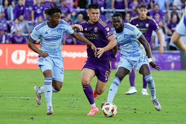 Orlando City's Cesar Araujo (5) tries to move the ball between Atlanta United's Ajani Fortune, left, and Jamal Thiare (29) during the first half of an MLS Semifinal Conference playoff soccer match, Sunday, Nov. 24, 2024, in Orlando, Fla. (AP Photo/John Raoux)