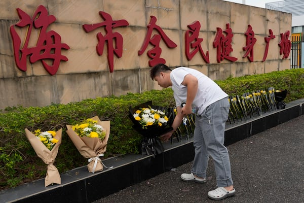 A man lays flowers outside the "Zhuhai People's Fitness Plaza" where a man rammed his car into people exercising at the sports center, in Zhuhai in southern China's Guangdong province on Wednesday, Nov. 13, 2024. (AP Photo/Ng Han Guan)