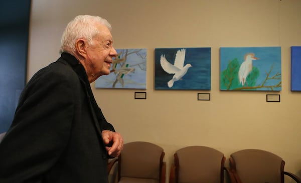 A 2017 file photo of former President Jimmy Carter looking over some of his own paintings of a green winged teal (from left), white dove, and cattle egret during an interview with The Atlanta Journal-Constitution at The Carter Center. Curtis Compton/ccompton@ajc.com