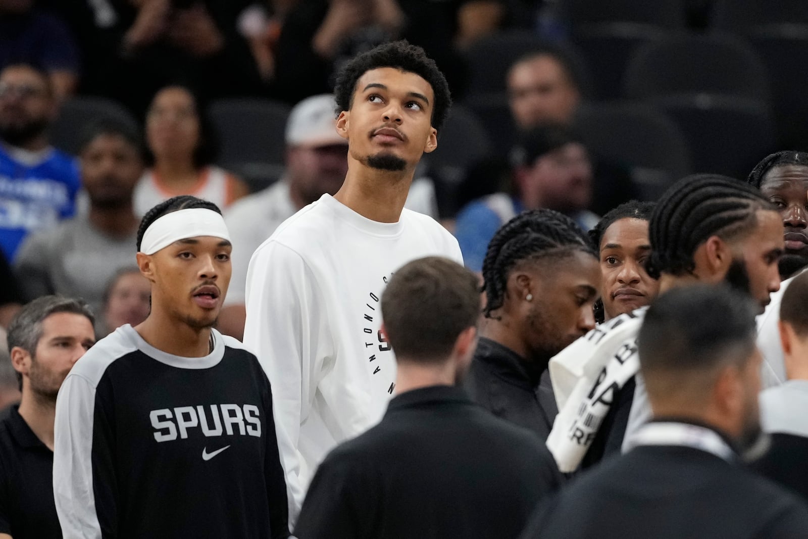 San Antonio Spurs center Victor Wembanyama, center, watches from the bench during the first half of a preseason NBA basketball game against the Oklahoma City Thunder in San Antonio, Monday, Oct. 7, 2024. (AP Photo/Eric Gay)