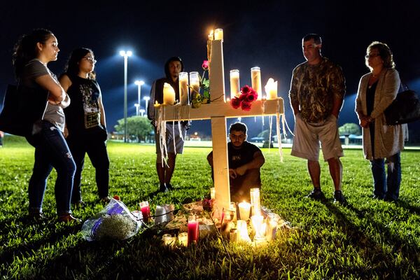 Mourners visit one of 17 crosses after a candlelight vigil for the victims of the shooting at Marjory Stoneman Douglas High School in Parkland on Thursday. (Greg Lovett / The Palm Beach Post)