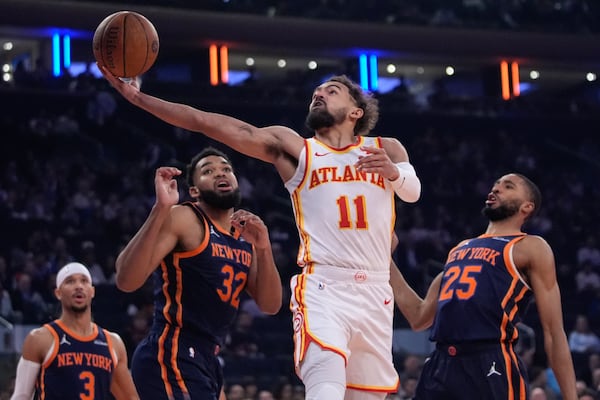 Atlanta Hawks' Trae Young (11) drives past New York Knicks' Mikal Bridges (25), Karl-Anthony Towns (32) and Josh Hart (3) during the first half of an Emirates NBA Cup basketball game Wednesday, Dec. 11, 2024, in New York. (AP Photo/Frank Franklin II)