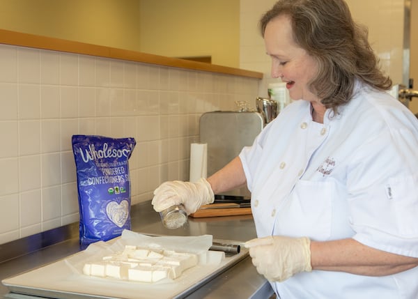 Chocolatier Julie Frazier sprinkles powdered sugar over Baileys Irish Cream Marshmallows at Maybird Confections in Alpharetta. (Aaliyah Man for The Atlanta Journal-Constitution)