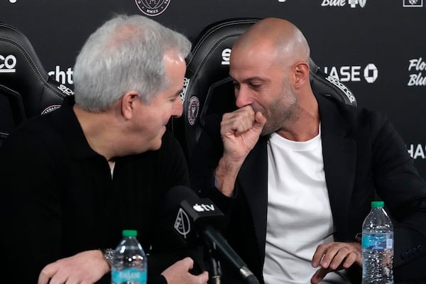 Inter Miami MLS soccer club managing owner and CEO Jorge Mas, left, looks on as new head coach Javier Mascherano coughs and struggling to get words out during an MLS soccer news conference, Tuesday, Dec. 3, 2024, in Fort Lauderdale, Fla. (AP Photo/Wilfredo Lee)