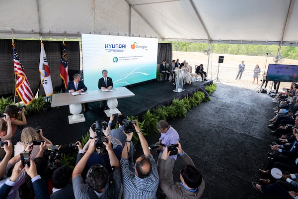 Governor Brian P. Kemp, center left, and Hyundai Motor Group President and CEO Jae Hoon Chang, center right, sign a ceremonial document at the announcement that the South Korean automotive giant is building an electric vehicle plant in Ellabell, Ga. Hyundai plans to build a multi-billion-dollar electric vehicle assembly and battery plant outside of Savannah that eventually could employ about 8,100 workers. (AJC Photo/Stephen B. Morton)