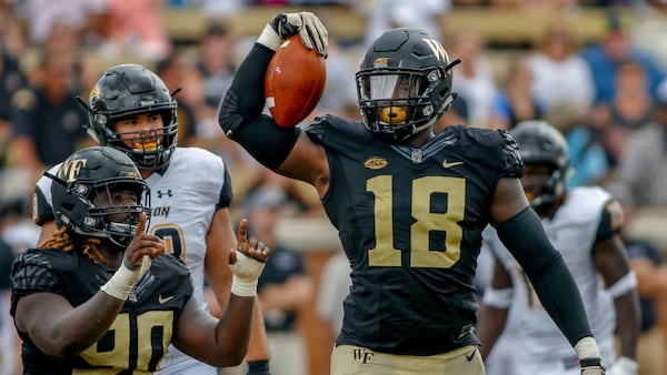 Wake Forest defensive linemen Carlos Basham Jr. (18) and Sulaiman Kamara celebrate after sacking Towson quarterback Tom Flacco in the first half Sept. 9, 2018, in Winston-Salem, N.C. Basham was selected to The Associated Press All-Atlantic Coast Conference football team, Tuesday, Dec. 10, 2019. (Nell Redmond/AP)