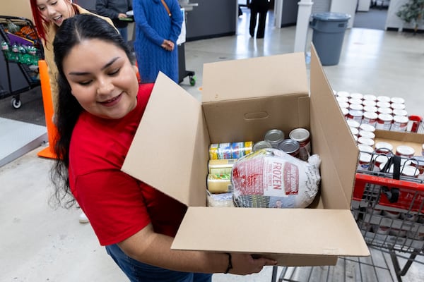 Volunteer Jazmin Williams, a media executive with Telemundo Atlanta, passed out a Thanksgiving box with turkey at Jonesboro Community Food Center in Jonesboro on Monday, November 18, 2024. The Atlanta Community Food Bank hosted its annual Thanksgiving Dish, during which families were able to get Thanksgiving-themed food boxes along with other groceries. (Arvin Temkar / AJC)