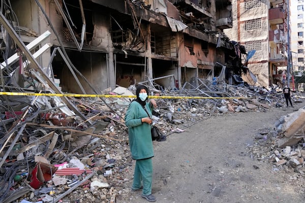 A woman stands in front of a building that was destroyed by an Israeli airstrike in Dahiyeh, in the southern suburb of Beirut, Lebanon, Monday, Nov. 11, 2024. (AP Photo/Hussein Malla)