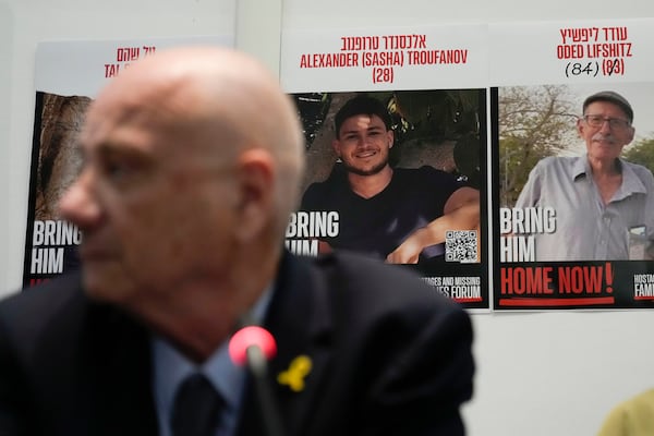 Louis Har, a former Israeli hostage, is backdropped by photos of hostage still held by Hamas during a press conference in Rome, Thursday, Nov. 14, 2024. (AP Photo/Alessandra Tarantino)