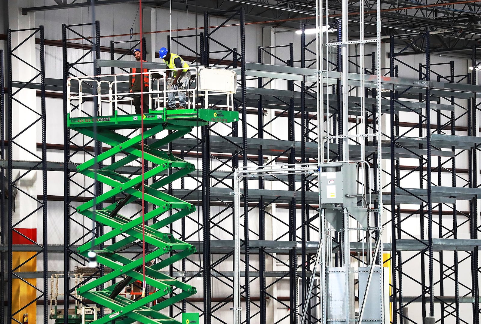 Construction workers assemble industrial storage shelving inside the massive new LTI Inc., food service equipment manufacturer building on Tuesday in Jonesboro. The expansion of the longtime Clayton company is a win for the county’s economic development team. Curtis Compton/ccompton@ajc.com