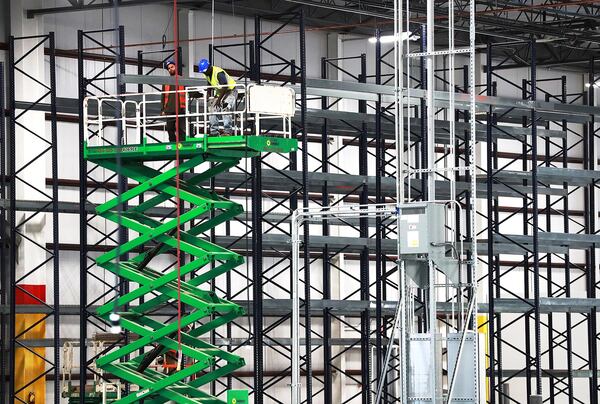 Construction workers assemble industrial storage shelving inside the massive new LTI Inc., food service equipment manufacturer building on Tuesday in Jonesboro. The expansion of the longtime Clayton company is a win for the county’s economic development team. Curtis Compton/ccompton@ajc.com