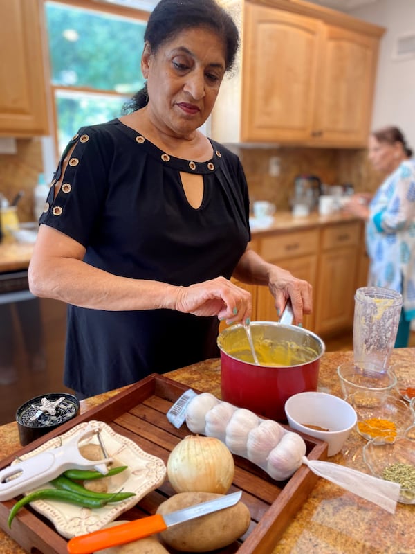 Purnima Malhotra, the mother of Atlanta chef Archna Malhotra Becker, stirs together the batter for paneer pakoras. (Wendell Brock for The Atlanta Journal-Constitution)