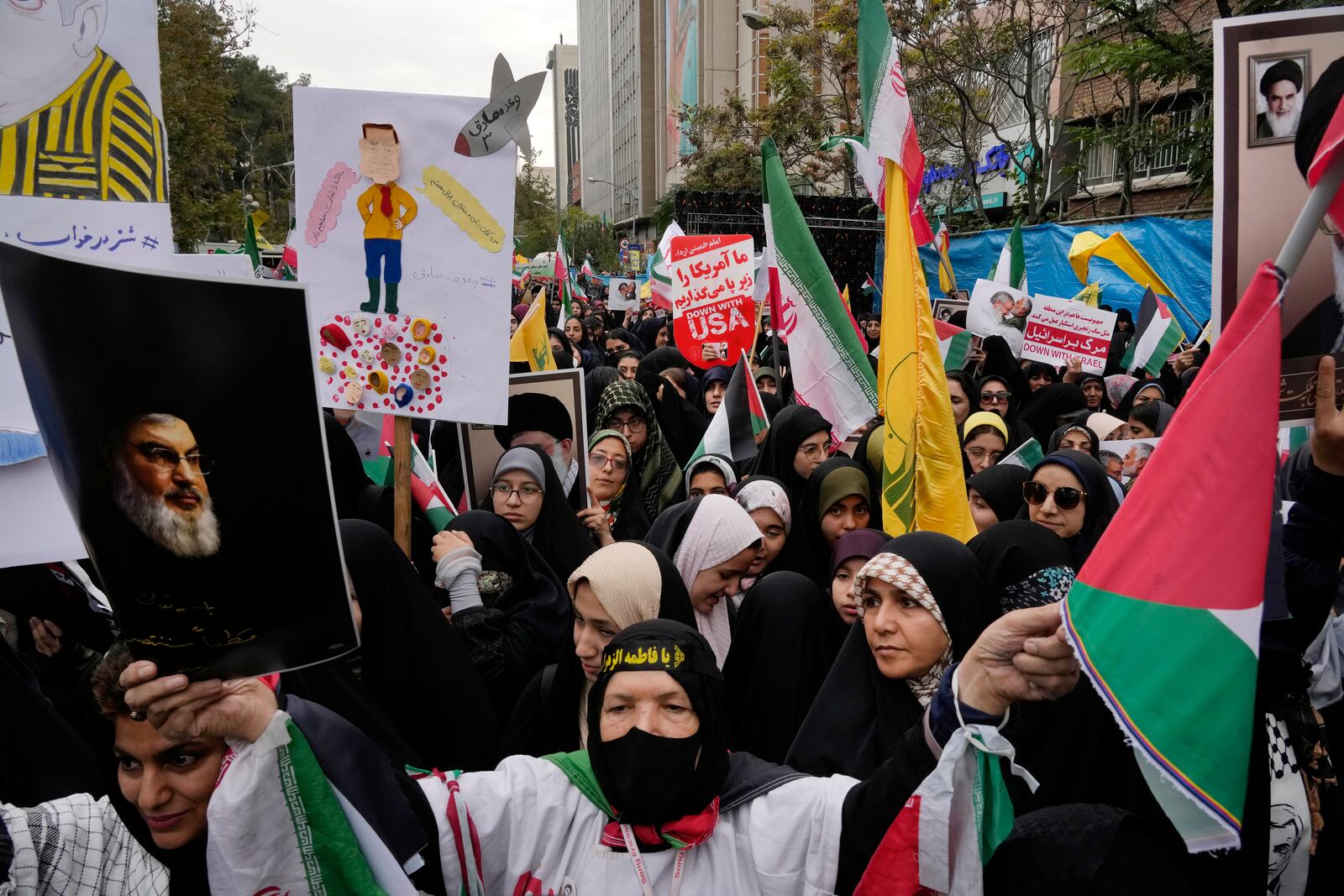 An Iranian demonstrator holds a poster of the slain Hezbollah leader, Hassan Nasrallah, and a Palestinian flag in an annual rally in front of the former U.S. Embassy in Tehran, Iran, Sunday, Nov. 3, 2024, marking the 45th anniversary of Iranian students' takeover of the embassy, starting a hostage crisis. (AP Photo/Vahid Salemi)