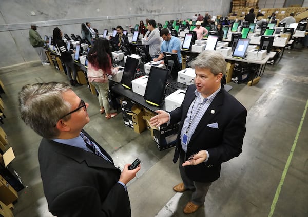 The AJC’s Mark Niesse (left) gets an inside look as the state's new voting machines are being tested and packed in an area warehouse on Tuesday, January 20, 2020, in Atlanta. CURTIS COMPTON / AJC