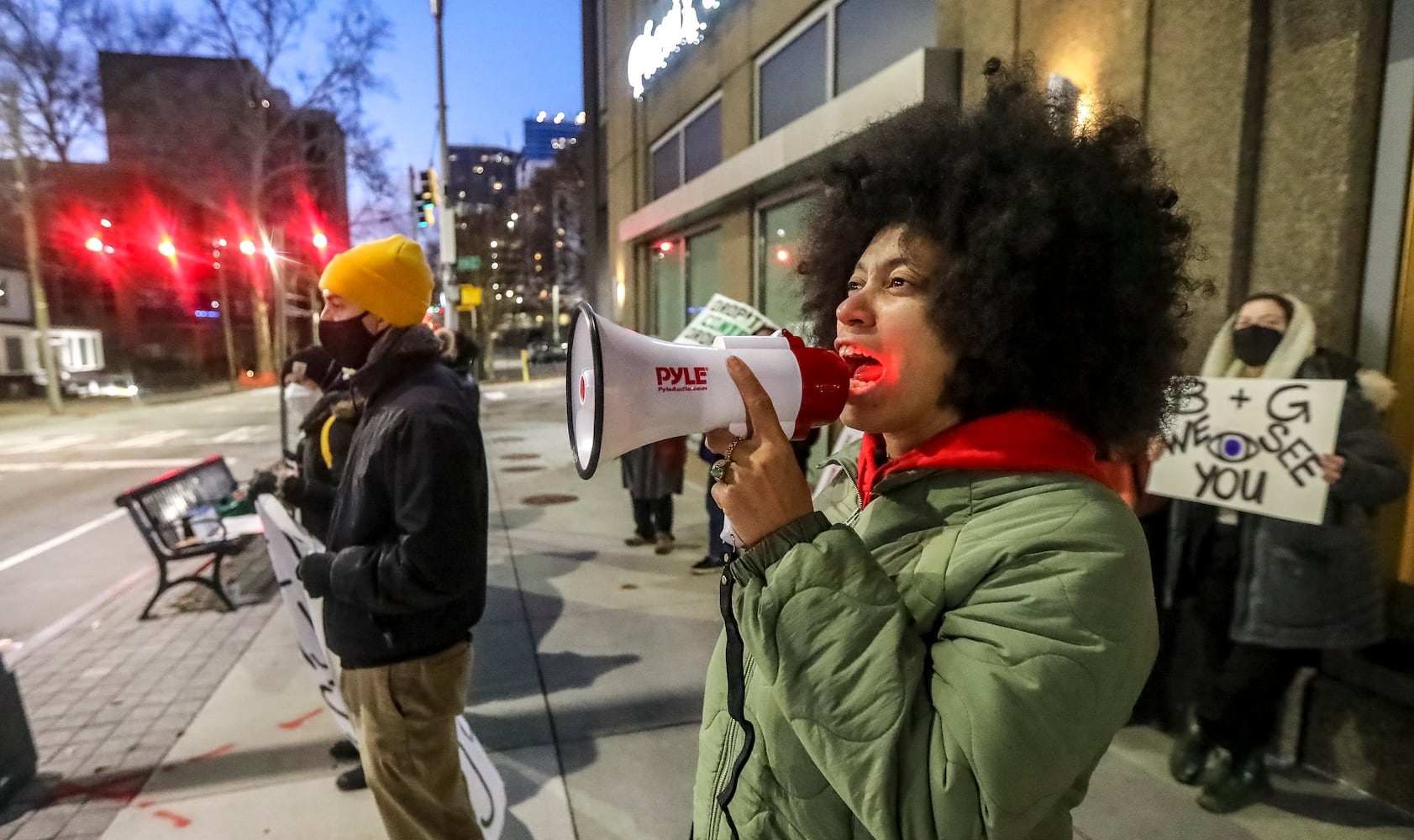 Mariah Parker with The People Stop Work Order uses a bullhorn to lead chants as law enforcement try to extricate two protesters from construction equipment. Two people locked themselves to construction equipment in Midtown to protest Atlanta’s planned public safety training center, causing a street to close amid the Monday morning commute, Jan. 29, 2024. The activists used reinforced bindings to lock their arms around the equipment at a Brasfield & Gorrie work site at 12th and Juniper streets. One person was locked to a construction elevator and the other to a boom. Both were released by 10:15 a.m. Juniper Street was closed to traffic for hours Monday morning before reopening around 11:30 a.m. SWAT team members were also at the scene for assistance in cutting the activists free. Brasfield & Gorrie is one of the contractors hired to build the training facility at the site of the old Atlanta Prison Farm in the south DeKalb County woods. Those opposed to the facility say its construction will damage the South River Forest and contribute to what they say is the militarization of the police department. (John Spink / John.Spink@ajc.com)

