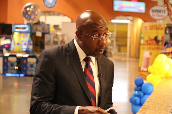 U.S. Sen. Raphael Warnock samples dishes from restaurants during his Monday visit to Plaza Las Americas in Lilburn. (Tyler Wilkins / tyler.wilkins@ajc.com)