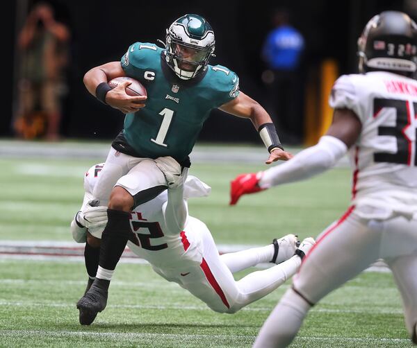 Philadelphia Eagles quarterback Jalen Hurts drags along Atlanta Falcons outside linebacker Adetokunbo Ogundeji for extra yardage during the first half Sunday, Sept. 12, 2021, at Mercedes-Benz Stadium in Atlanta. The Eagles won 32-6. (Curtis Compton / Curtis.Compton@ajc.com)