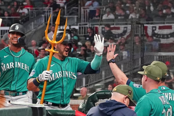 Seattle Mariners' Eugenio Suarez, second from left, holds a trident as he is greeted at the dugout after hitting a two-run home run in the seventh inning of a baseball game against the Atlanta Braves , Saturday, May 20, 2023, in Atlanta. (AP Photo/John Bazemore)