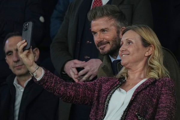 Former England soccer player David Beckham, center, poses for a photo with a spectator before the Champions League round of 16 first leg soccer match between Paris Saint-Germain and Liverpool at the Parc des Princes in Paris, Wednesday, March 5, 2025. (AP Photo/Aurelien Morissard)