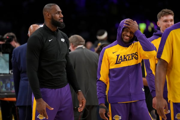 Los Angeles Lakers forward LeBron James, left, and his son, guard Bronny James warm up prior to an NBA basketball game against the Phoenix Suns in Los Angeles, Friday, Oct. 25, 2024. (AP Photo/Eric Thayer)