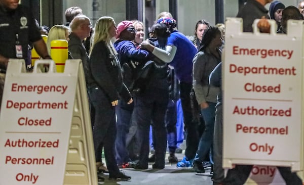 Medical workers embrace one another after the closing Atlanta Medical Center’s emergency room in October 2022. Wellstar, which closed the hospital, has drawn criticism for closing the safety-net facility when it is expanding in other parts of the state. (John Spink / John.Spink@ajc.com) 

