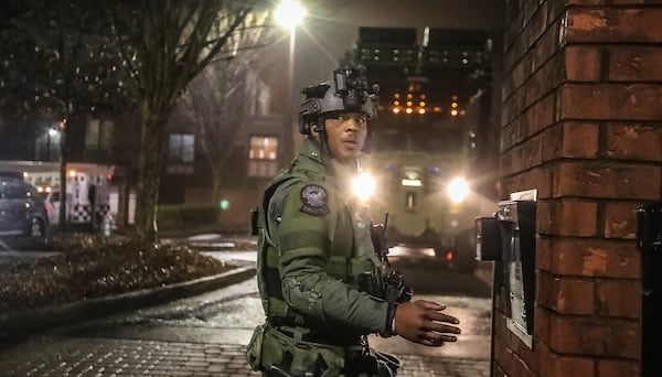 An Atlanta police SWAT member looks on from the parking lot of the Landing Square apartments, where the team was sent following a mother's report that her daughter was inside an apartment and might be in danger.