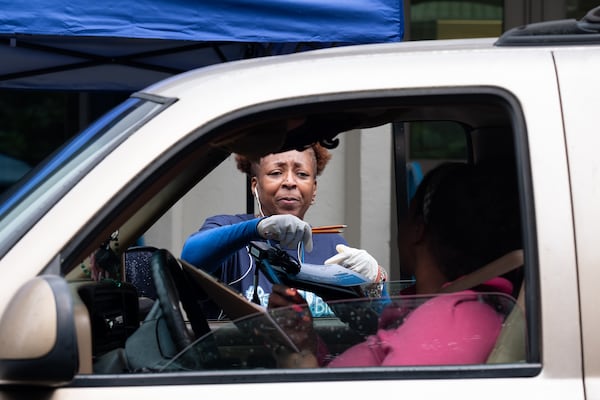 Janice Alexander, a kindergarten parapro at Harper-Archer Elementary School, hands a computer to a parent who came to the school Tuesday afternoon March 24, 2020. The school was issuing devices to students so they could continue studying during the coronavirus pandemic. 