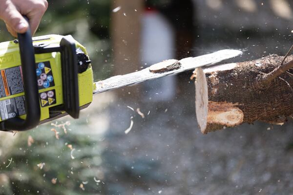 Owner Jack Faught trims the base of a Christmas tree after it was put through a Baler at his Trees For Tuition Christmas tree lot in Virginia Highland on Saturday, November 25, 2023. (Steve Schaefer/steve.schaefer@ajc.com)